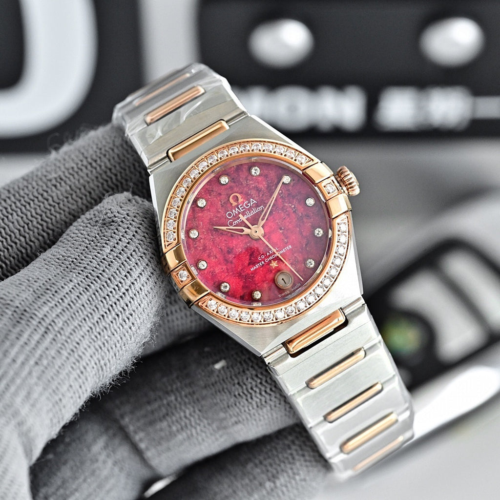 Omega wristwatch with red-pink dial, rose-gold bezel with diamond accents, and metal bracelet.