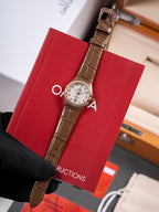 Omega wristwatch, brown leather strap with silver dial and bezel, held by black glove