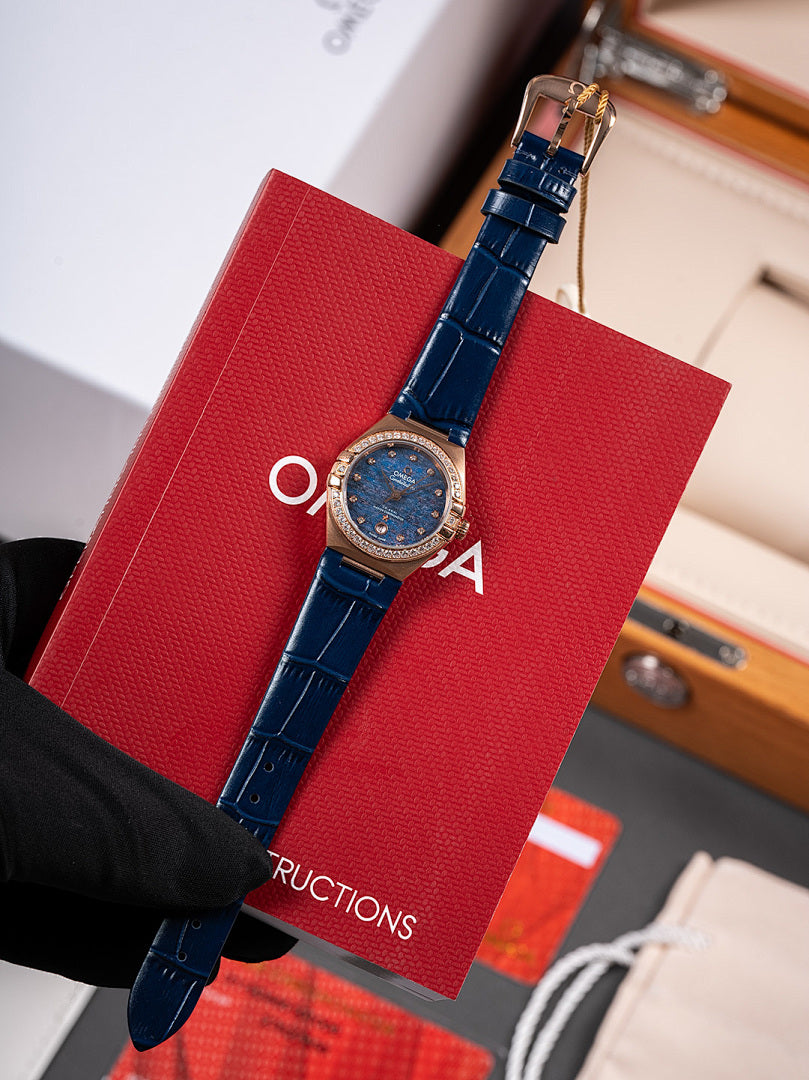 Omega wristwatch, blue leather strap with blue dial and bezel, held in black glove