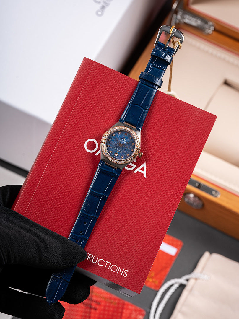 Omega wristwatch, blue leather strap with blue dial and bezel, held by black glove
