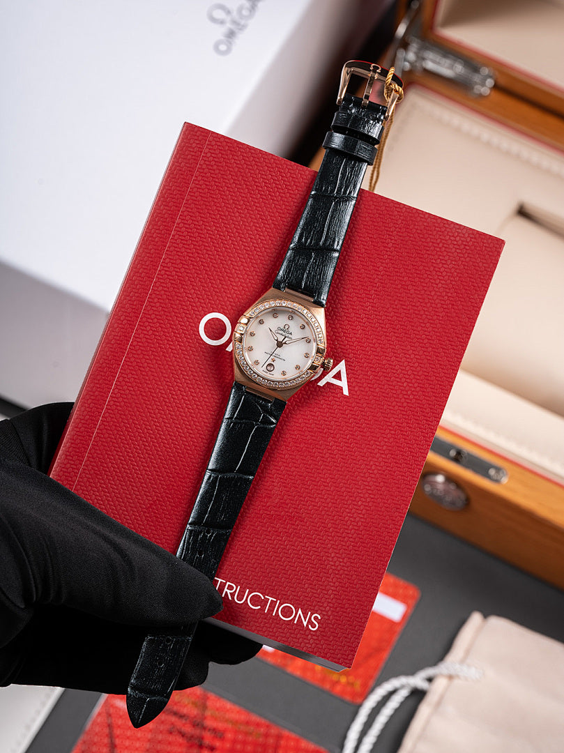Omega wristwatch, black leather strap with silver dial and bezel, held by black glove