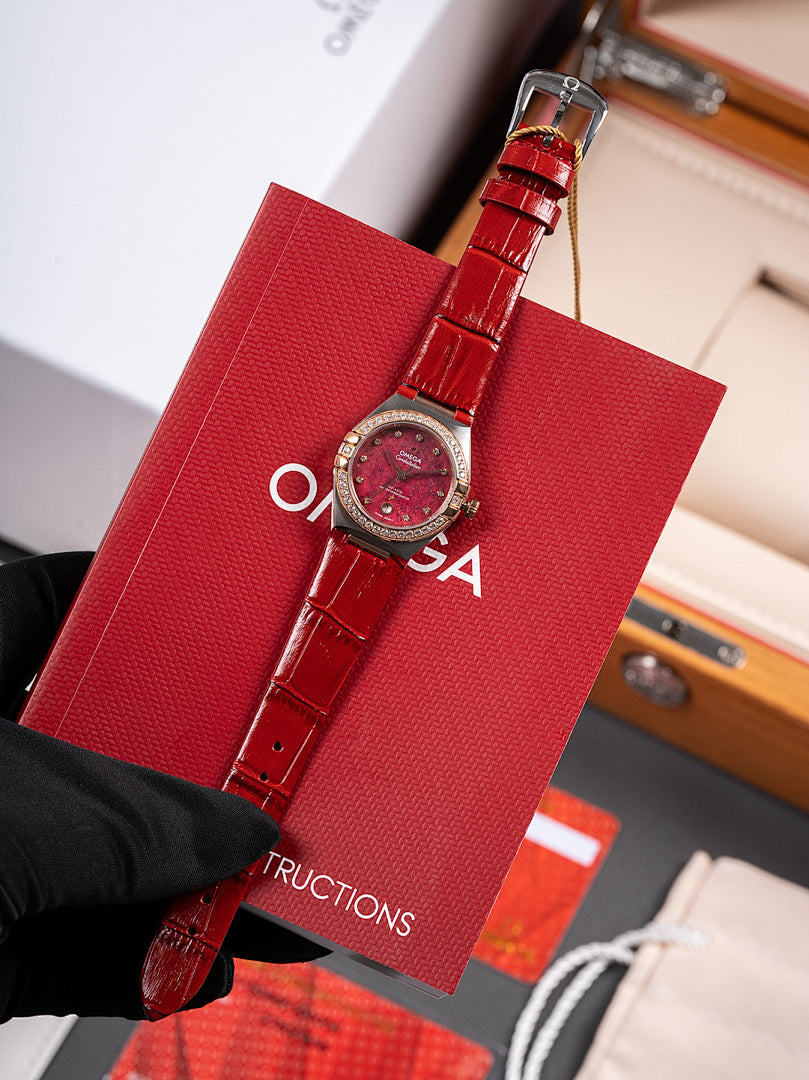 Omega wristwatch with red dial, red leather strap and clasp, held by black glove