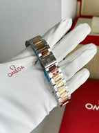 Two-tone metal wristwatch bracelet held by white gloves, side view