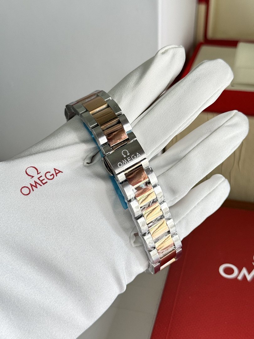 Two-tone metal wristwatch bracelet held by white gloves, side view