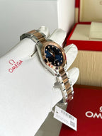 Two-tone metal wristwatch with dark blue dial on white gloves, angled view