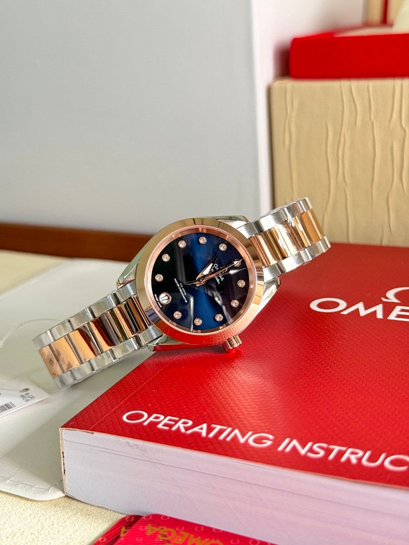 Two-tone wristwatch with dark blue dial and gold-tone accents on a red box
