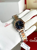 Two-tone metal wristwatch with dark blue dial on white gloves, angled front view