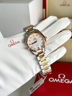 Omega wristwatch with two-tone metal bracelet and light dial on white glove