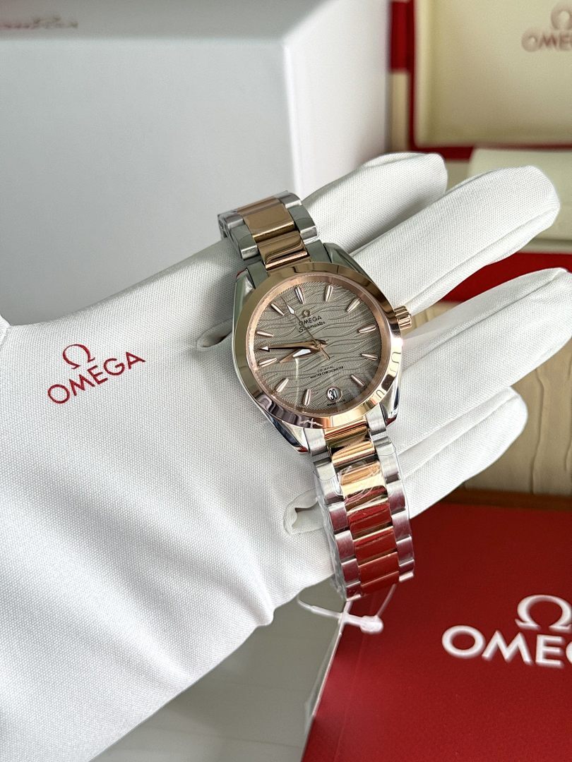 Omega wristwatch with two-tone metal bracelet and gray dial on white glove