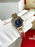 Omega wristwatch with two-tone metal bracelet and deep blue dial on white glove