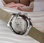 Round watch face with engraved medallion and multiple-tone strap, silver case and bezel