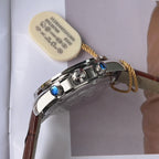 Chronograph watch with brown leather strap, gold chain, blue-capped pushers