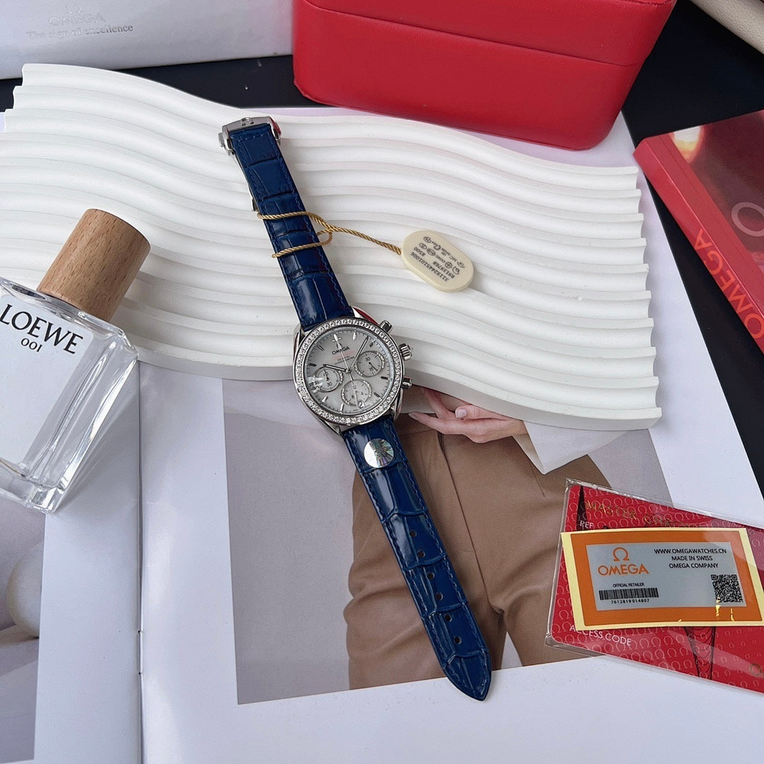 Omega wristwatch with blue leather strap and silver chronograph dial, held in hand