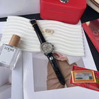 Omega chronograph watch with black leather strap and silver dial, held in hand.