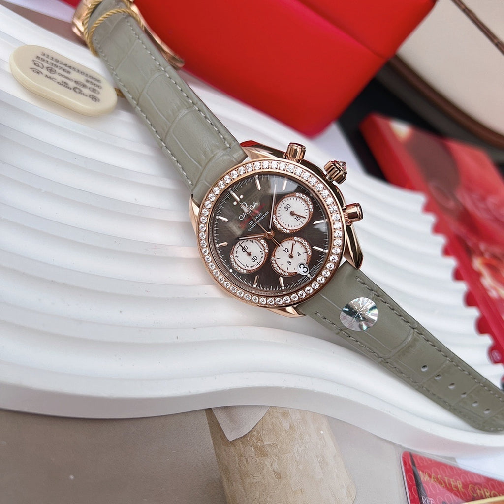 Omega chronograph wristwatch, dark dial with subdials, rose gold bezel stones, gray leather strap