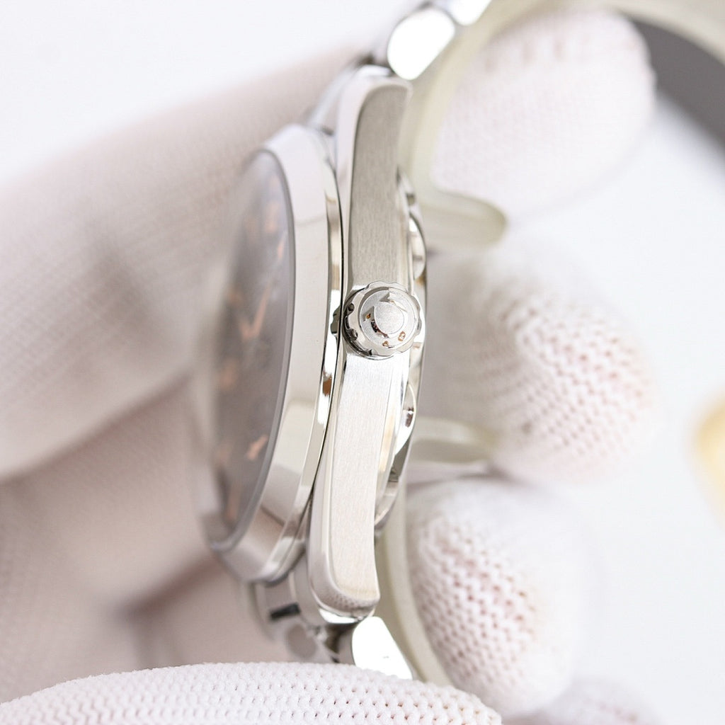 Omega wristwatch side view, silver case and crown detail on white cloth.