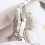 Omega wristwatch side view, silver case and crown detail on white cloth.