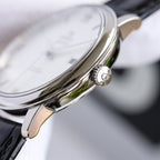 Wristwatch with silver crown and black leather strap, close-up side view