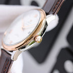Rose gold-tone watch side view with crown and black leather strap