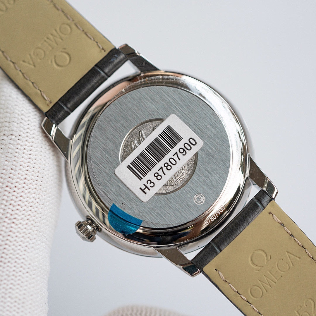 Omega De Ville watch case back with barcode label on brushed metal surface