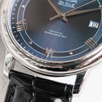 Omega De Ville wristwatch close-up of blue dial, silver hands, Roman markers and date at 12