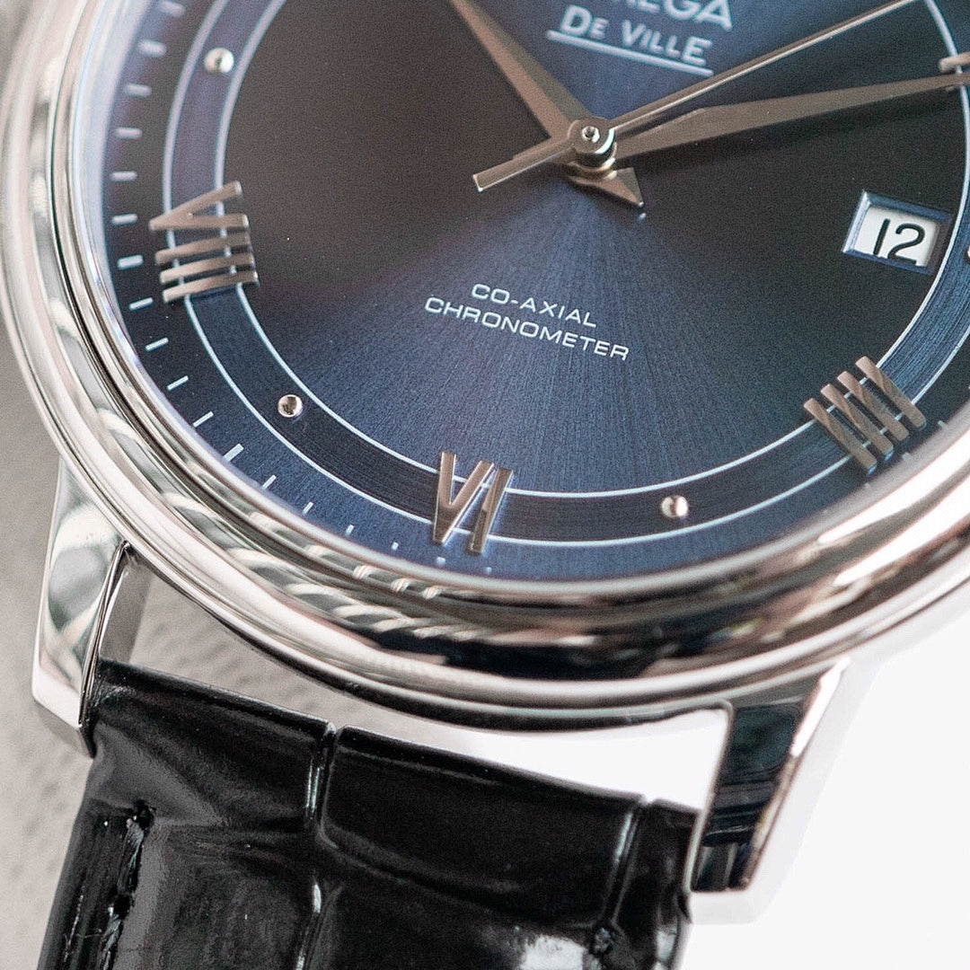 Omega De Ville wristwatch close-up of blue dial, silver hands, Roman markers and date at 12
