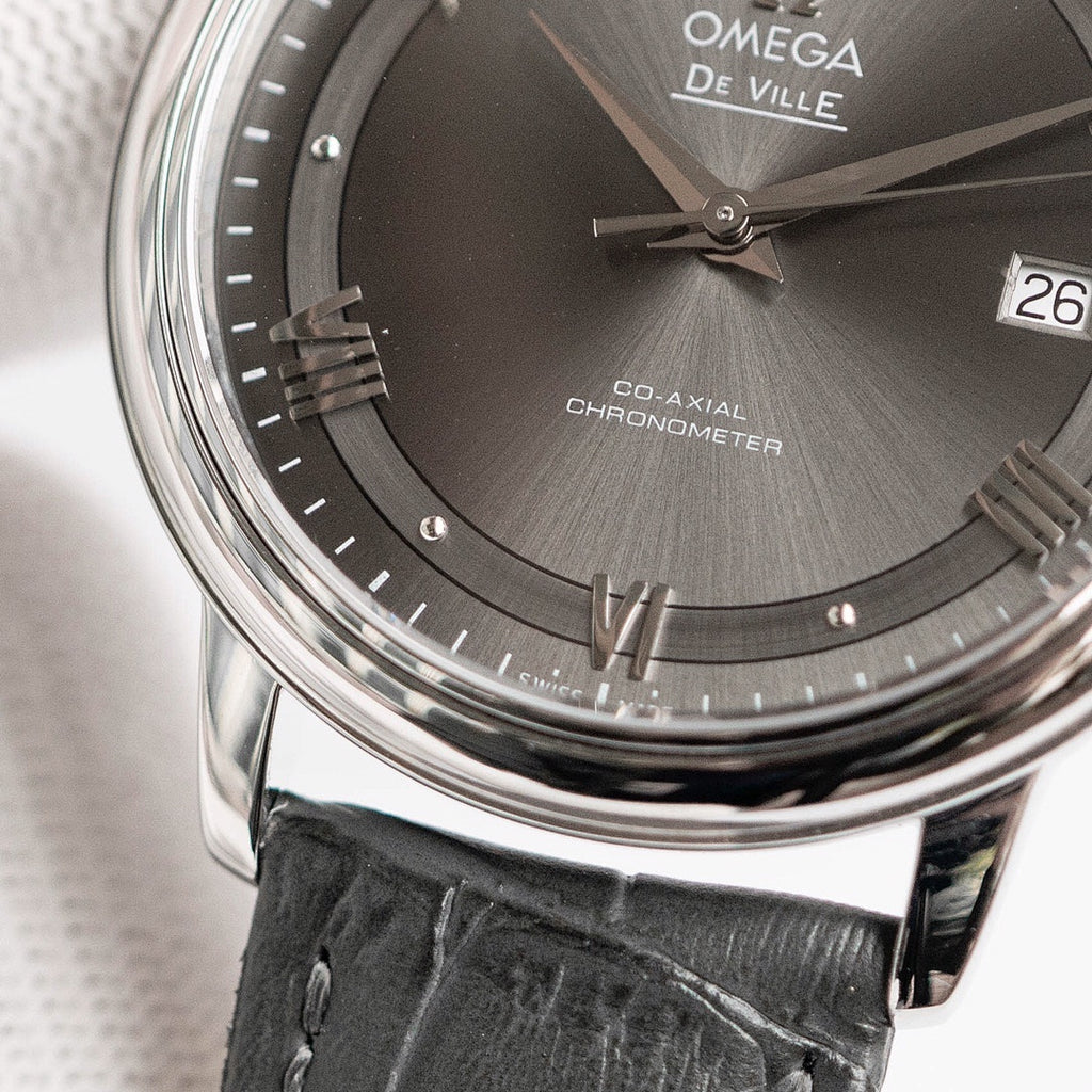 Omega De Ville dial close-up with Roman numerals, date 26, black leather strap.