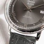 Omega De Ville dial close-up with Roman numerals, date 26, black leather strap.