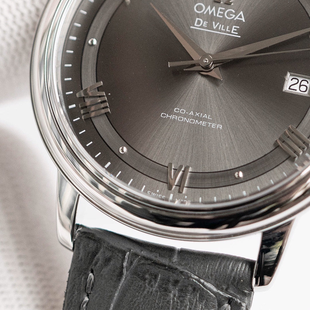 Omega De Ville dial close-up with Roman numerals, date 26, black leather strap.