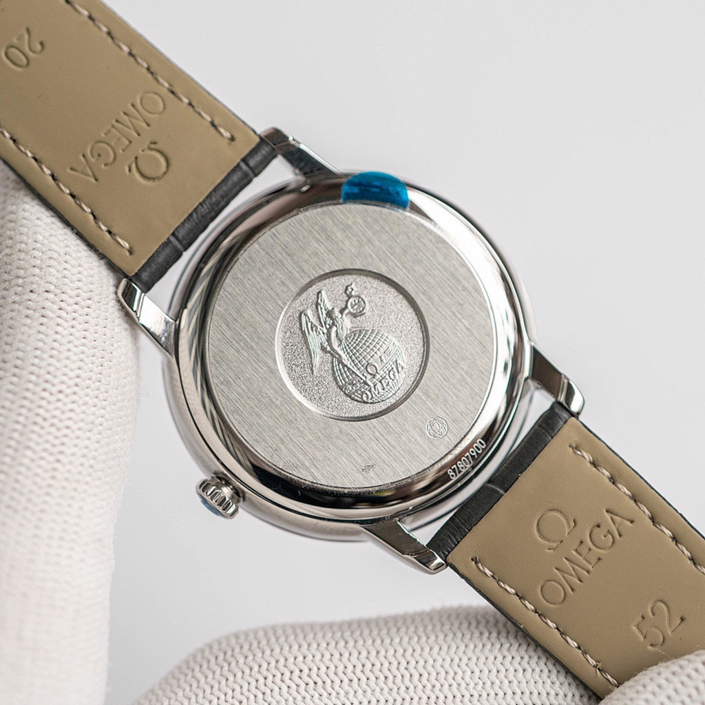 Omega De Ville watch with engraved case back and tan leather strap.