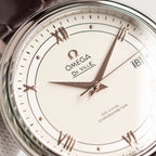 Omega De Ville watch face close-up with white dial, gold markers, hands, date at 18