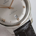 Omega watch close-up with champagne dial, gold hands, and black leather strap