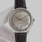Omega dress watch with champagne dial, black leather strap, and stainless steel case