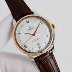 Analog wristwatch, light dial, gold-tone case, brown leather strap, day-date window