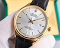 Omega wristwatch with black leather strap and silver dial, gold-tone bezel and baton markers