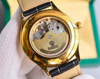 Omega wristwatch caseback with gold-tone metal and visible mechanical movement under clear cover