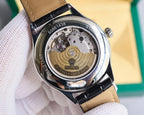 Omega wristwatch caseback view with exposed movement, black and tan leather strap.