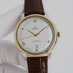 Omega watch with gold tone case, white dial, brown leather strap, Roman numerals, date 22.