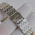 Two-tone metal watch bracelet with clasp detail on a white cuff