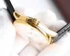 Omega watch gold case side with crown and black leather strap