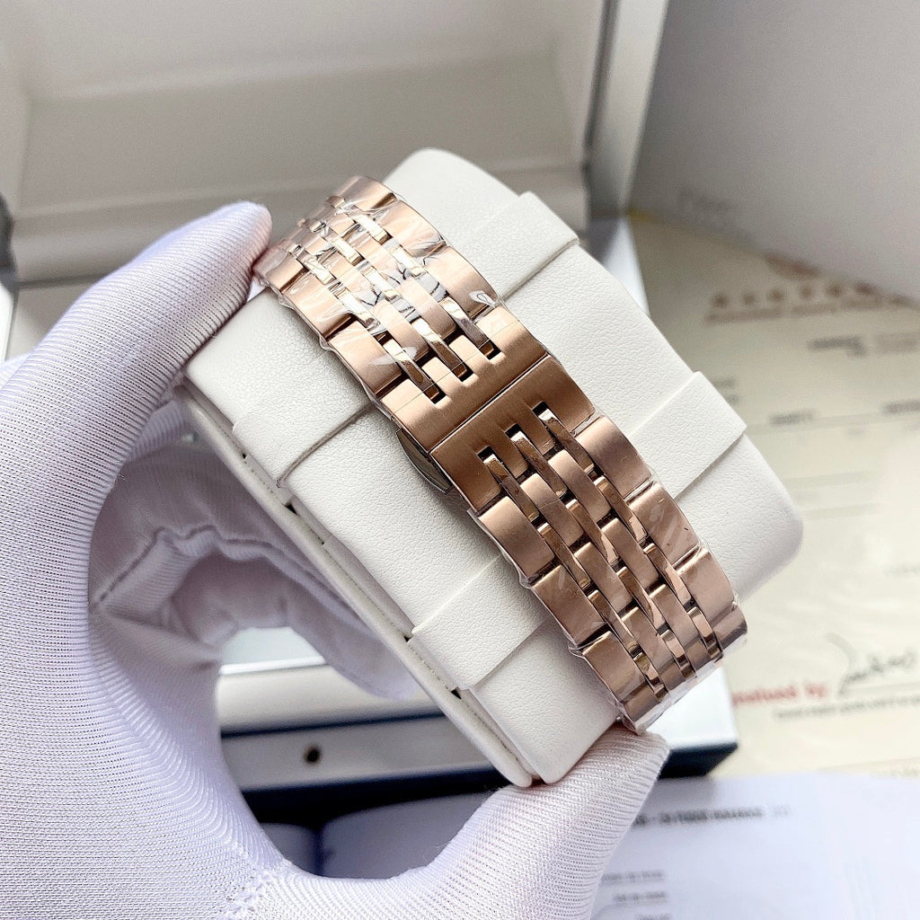 Omega watch rose-gold link bracelet on white watch pillow, side view of case.