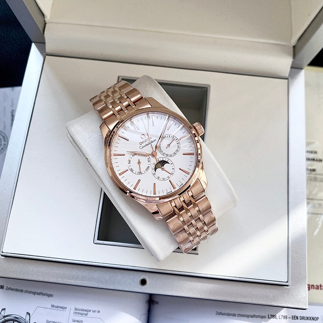 Rose-gold tone wristwatch on a white cushion inside a gift box with metal link bracelet.