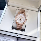 Rose-gold tone wristwatch standing upright in its box with white dial and metal link bracelet.