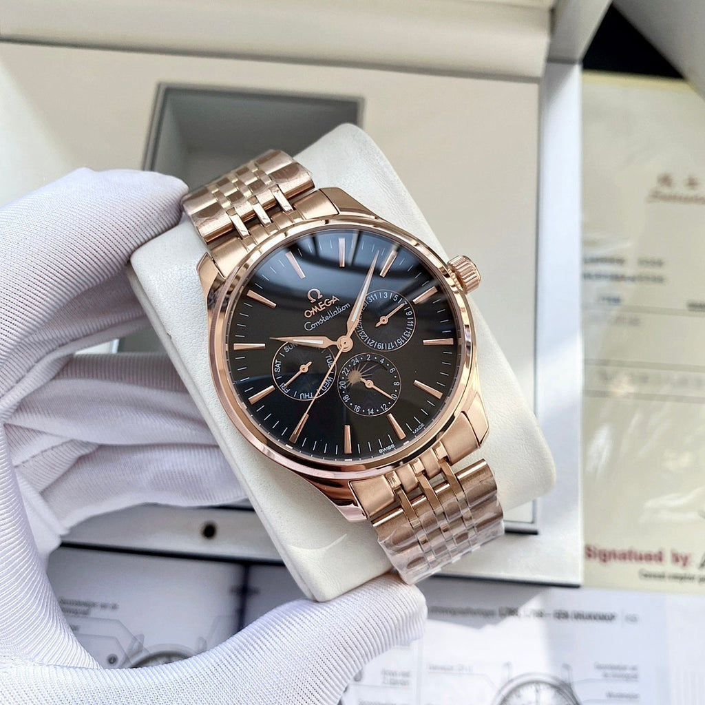 Rose-gold tone wristwatch with dark blue dial, subdials, and metal link bracelet in box.