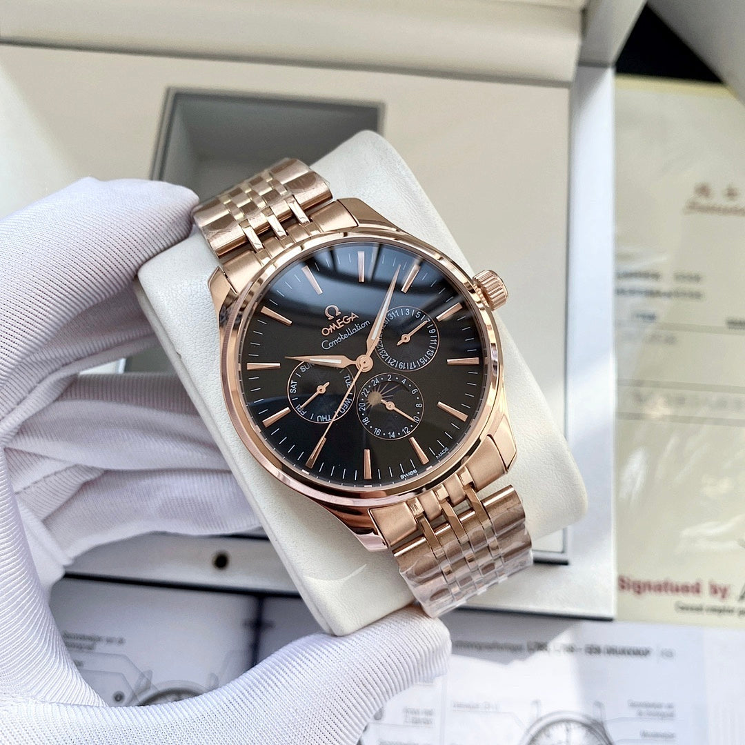 Rose-gold tone wristwatch with dark blue dial, subdials, and metal link bracelet in box.