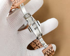 Rose gold and silver Omega wristwatch with metal bracelet, side view on white cloth
