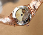 Rose gold Omega wristwatch with exposed movement on caseback, on white cloth