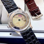 Wristwatch case back with visible movement, on black leather strap