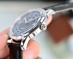 Automatic watch with silver bezel and black leather strap, crown visible at right