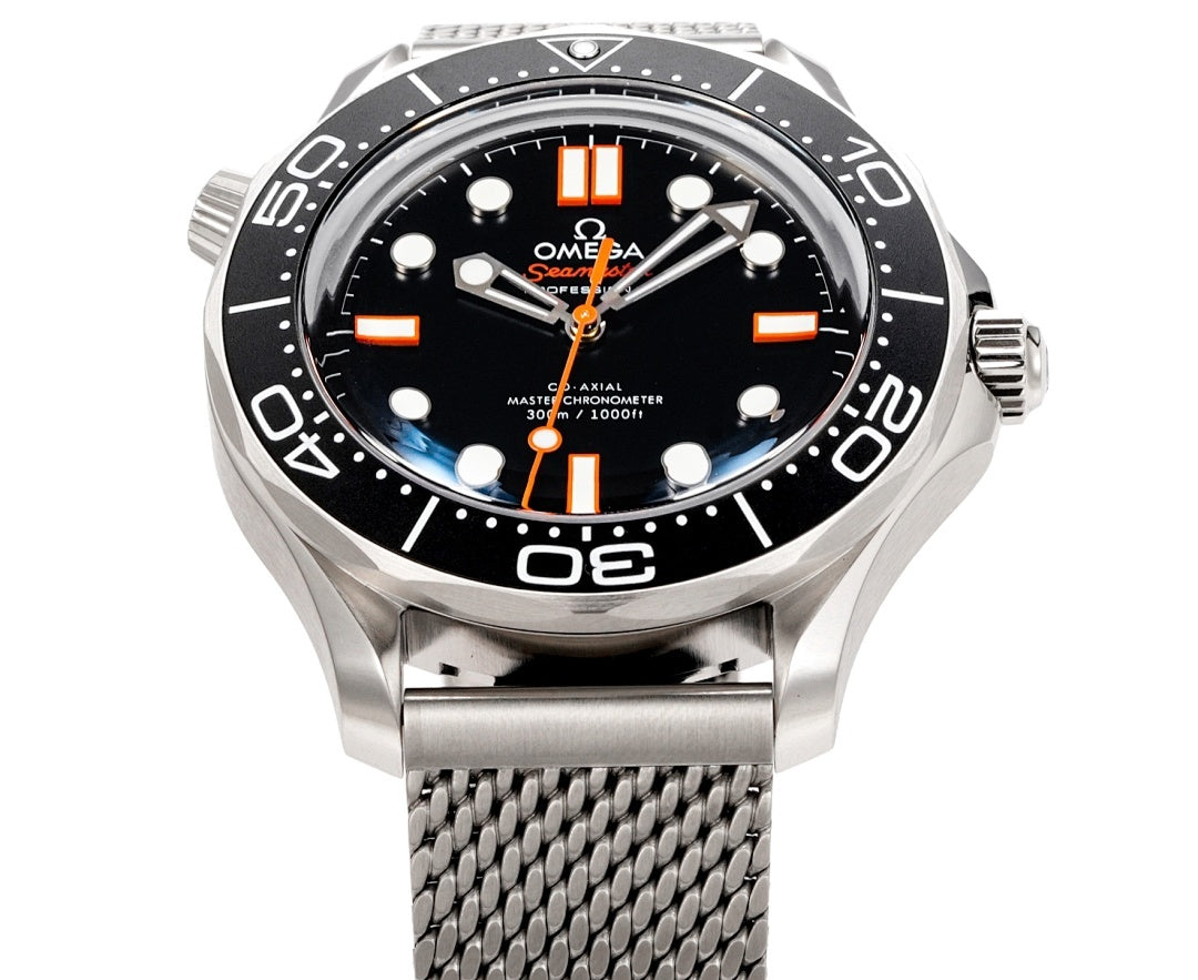 Wristwatch front view with black dial, orange markers, and stainless mesh band